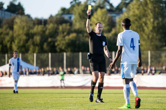 domare Jonas Eriksson delar ut ett gult kort