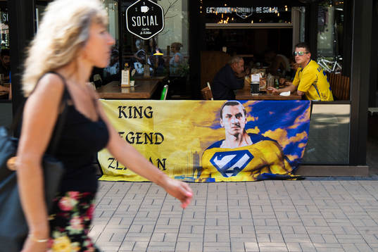 En kvinna passerar ett svenskt fan med en banderoll med en