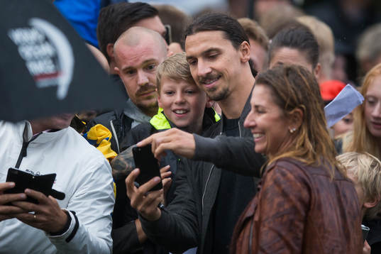Zlatan Ibrahimovic tar en bild med en ung supporter