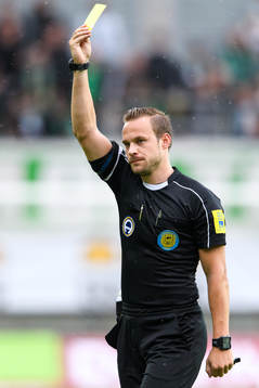 Domare Kristoffer Karlsson delar ut ett gult kort