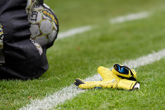 Målvaktshandskar och bollar före fotbollsmatchen i