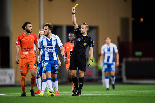 Domare Kristoffer Karlsson delar ut ett gult kort