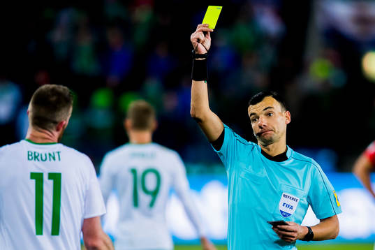 Chris Brunt of Northern Ireland is shown the yellow card by