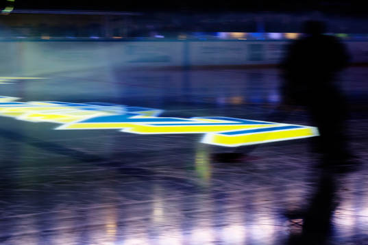 Skuggan av en spelare syns mot en projicerad HV71-logotyp