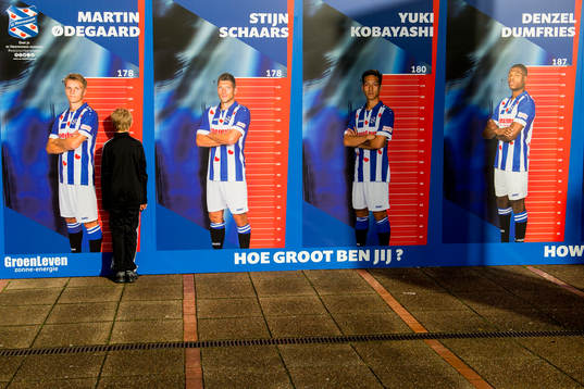 A boy measures his height against Martin Ødegaard of