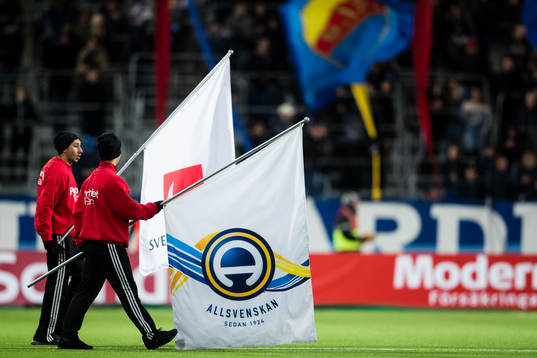 Två flaggbärare går in på plan innan fotbollsmatchen i