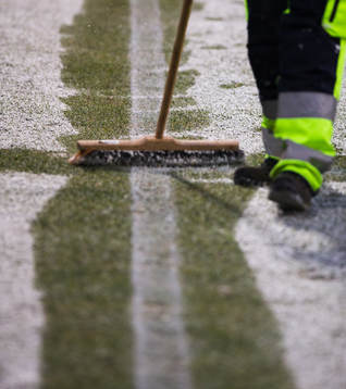 En vaktmästare borstar bort snö från planen