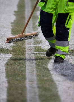 En vaktmästare borstar bort snö från planen