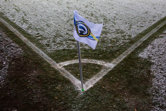 Snö på gräset runt hörnflaggan