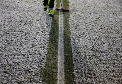 En vaktmästare borstar bort snö från planen