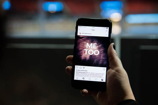 En kvinna kollar på sin mobil med visandes en #metoo bild