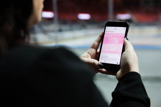 En kvinna kollar på sin mobil med visandes en #metoo bild