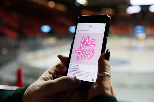 En kvinna kollar på sin mobil med visandes en #metoo bild