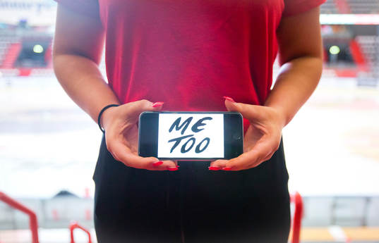 En tjej håller upp en telefon med texten Metoo