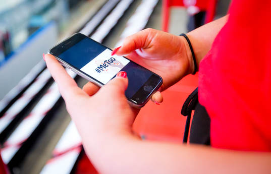 En tjej håller upp en telefon med texten Metoo