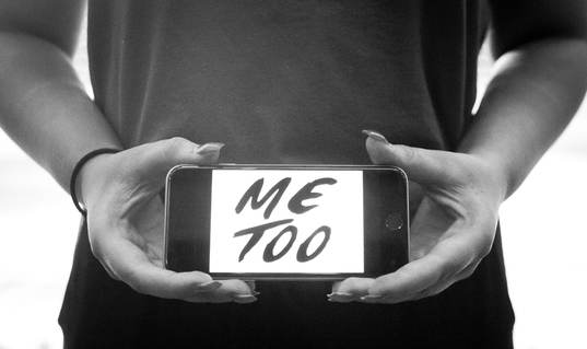 En tjej håller upp en telefon med texten Metoo