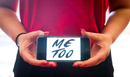 En tjej håller upp en telefon med texten Metoo