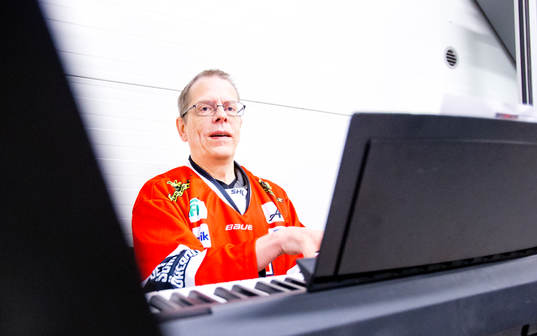 En person spelar på en hockeyorgel i Örebrotröja