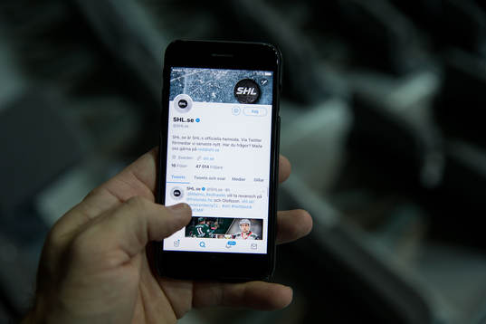 s twitter på sin mobil innan ishockeymatchen i SHL mellan