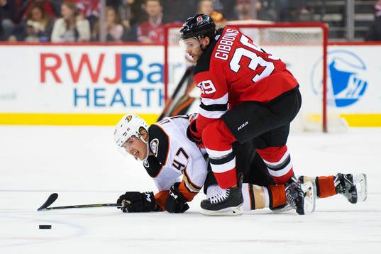 Ducks Hampus Lindholm tacklas av Devils Brian Gibbons