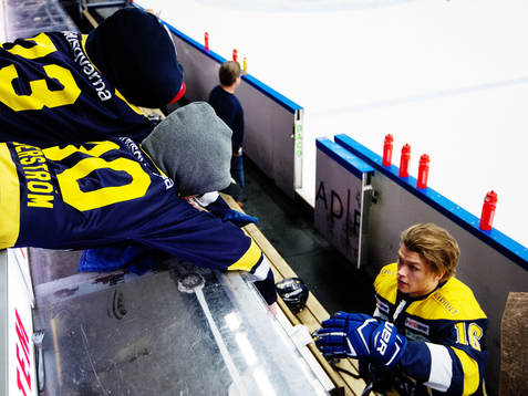 Två unga HV71-supportrar sträcker händerna mot Tom