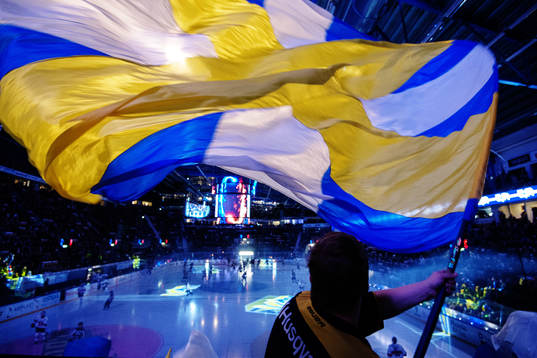 En HV71-supporter vevar med en blågul flagga