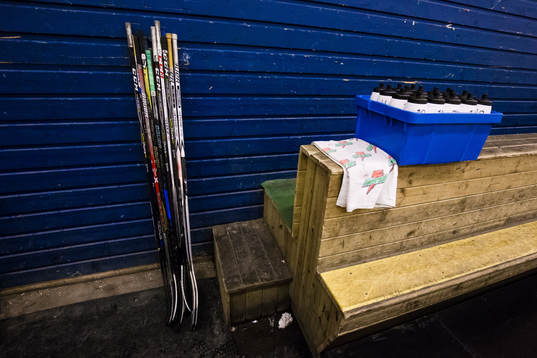 Ishockeyklubbor vid ett avbytarbås innan ishockeymatchen i