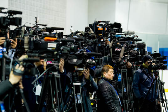 TV photographers are covering a press conference with the