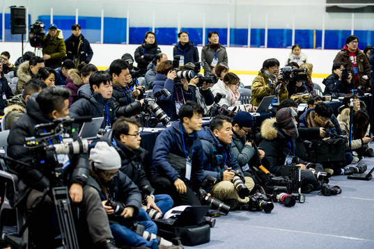Press photographers are covering a press conference with