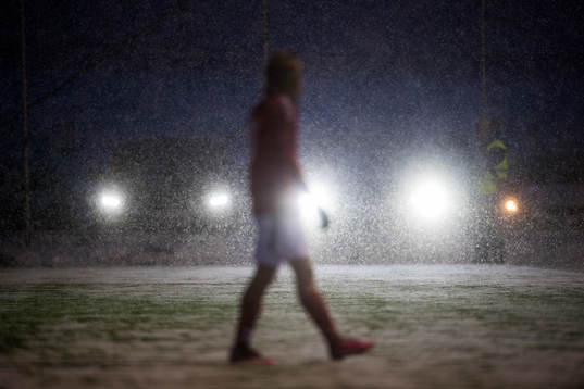 En spelare syns i snöfall och strålkastare från bilar