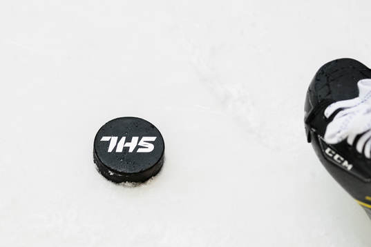 En puck med SHL tryckt på och en skridsko