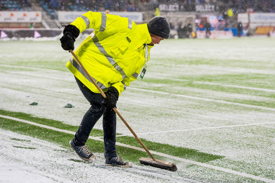 A worker clearing of snow from the field