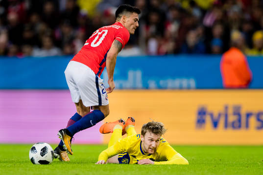 Sveriges Emil Forsberg faller i en duell med Chiles Charles