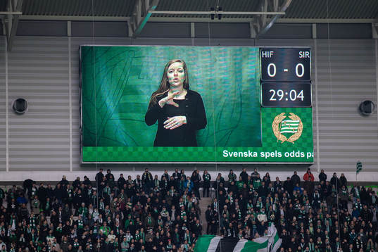 En kvinna teckentolkar på ljustavla