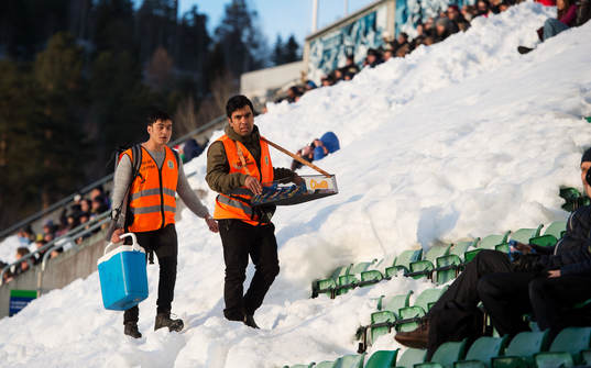 Försäljare vandrar över en snöbeklädd läktare