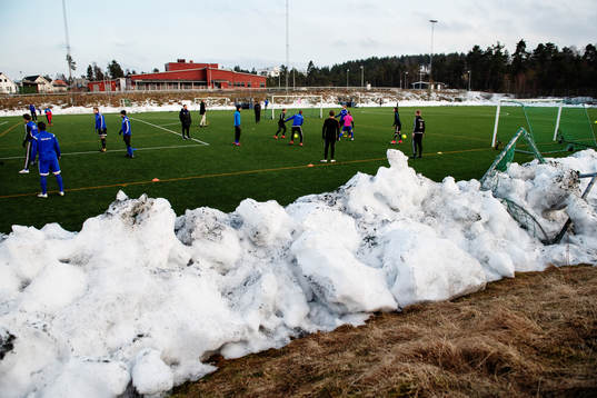Spelarna värmer upp på plan med snövallar intill