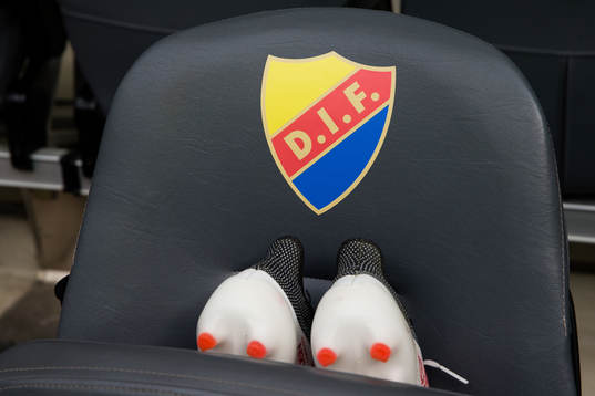 Djurgårdens emblem och ett par fotbollsskor på en stol