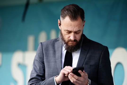 Fotbollskanalens Olof Lundh tittar på sin mobiltelefon