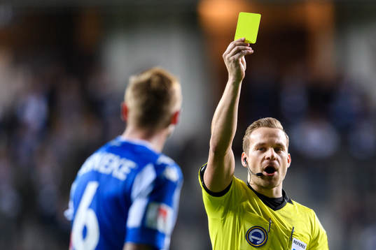Domare Kristoffer Karlsson delar ut ett gult kort