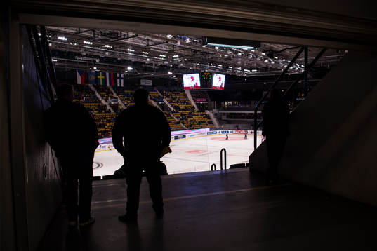 Två personer står i gången och ser på hockey