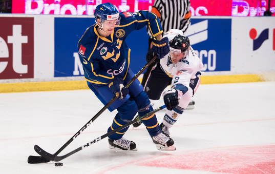 Sveriges John Klingberg med pucken i en duell med Finlands