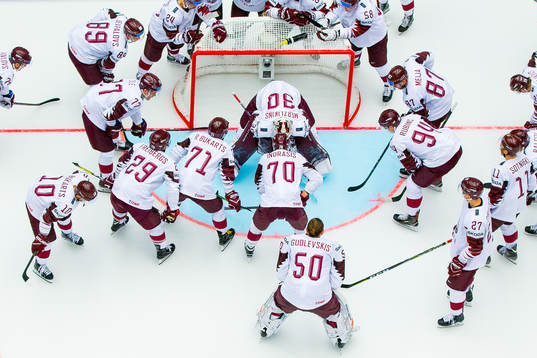 Players of Latvia gather around goaltender Elvis Merzlikins