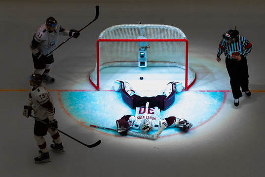 Goaltender Elvis Merzlikins of Latvia is illuminated by a