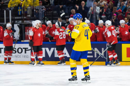 Sveriges Hampus Lindholm deppar medan Schweiz spelare jublar