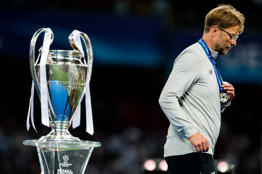 Jürgen Klopp, head coach of Liverpool, walks by the trophy