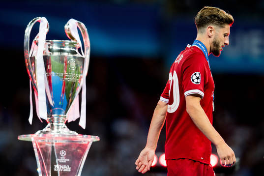 Adam Lallana of Liverpool walks dejected past the trophy