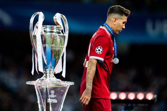 Roberto Firmino of Liverpool walks by the trophy
