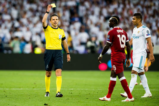 Referee Milorad Mazic of Serbia gives a yellow card