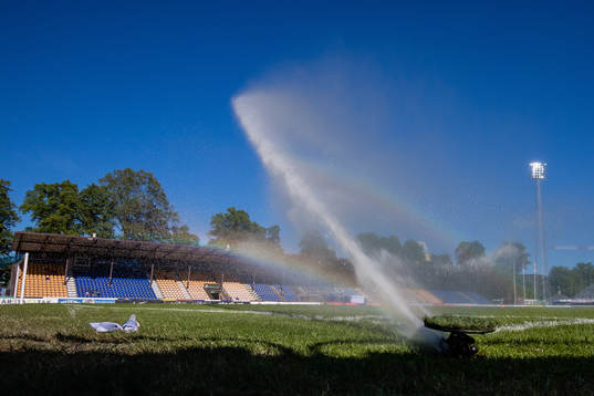 En vattenspridare vattnar fotbollsplanen med naturgräs på
