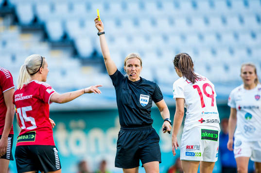 Domaren Sara Persson höjer ett gult kort framför Limhamn